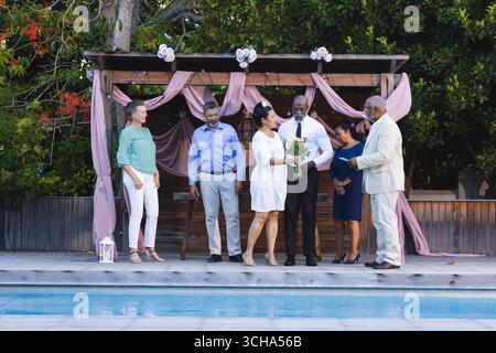 Lors du mariage, de la célébration, des amis seniors divers échangent des sourires et des rires au bord de la piscine. célébration, bonheur, style de vie, loisirs, amitié, po Banque D'Images