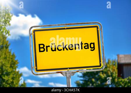 Bavière, Allemagne - 1er septembre 2025 : PHOTOMONTAGE, panneau jaune avec l'inscription : BRÜCKENTAG, devant le ciel bleu et les arbres verts. Indication d'un jour de congé entre jour férié et week-end *** FOTOMONTAGE, Gelbes Schild mit der Aufschrift : BRÜCKENTAG, vor blauem Himmel und grünen Bäumen. Hinweis auf einen arbeitsfreien Tag zwischen Feiertag und Wochenende Banque D'Images