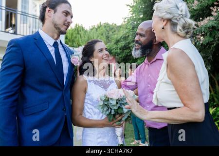 Mariée et mariée souriant avec les invités, célébrant le jour joyeux de mariage en plein air. Mariage, célébration, bonheur, amour, joyeux, raccord Banque D'Images