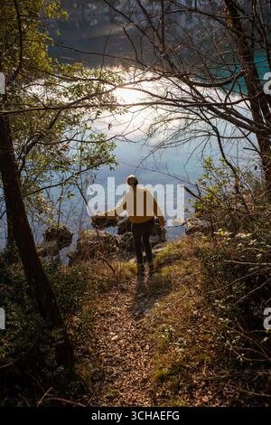 Une femme marchant près d'un lac dans un paysage automnal. L'image, avec le reflet du soleil sur l'eau. Banque D'Images