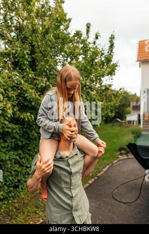 Fille ludique assise sur l'épaule du père dans l'allée Banque D'Images