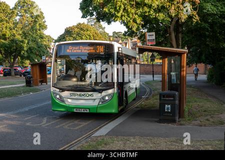 Un bus arrivant à un arrêt à Saffron Walden, Essex, Angleterre avec un abri de bus en bois. Banque D'Images
