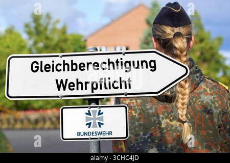 Bavière, Allemagne - 1er septembre 2025 : PHOTOMONTAGE, panneau de signalisation avec inscription : Gleichberechtigung Wehrpflicht, et logo de la Bundeswehr, derrière lui une femme soldat en uniforme de camouflage avec queue de cochon tressée. Image symbolique du service militaire obligatoire pour les femmes en Allemagne *** FOTOMONTAGE, Wegweiser Schild mit Aufschrift : Gleichberechtigung Wehrpflicht, und Bundeswehr-logo, dahinter eine Soldatin in TarnUniform mit geflochtenem Zopf. Symbolbild Wehrpflicht für Frauen in Deutschland Banque D'Images