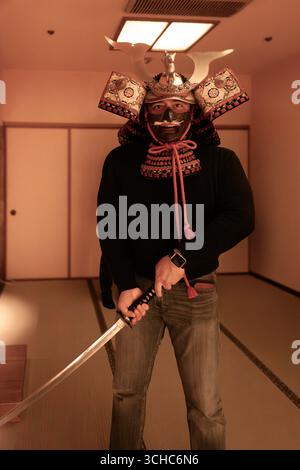 Homme mexicain portant un casque kabuto ou japonais tenant une épée katana se transportant dans le temps au XIXe siècle avec la tenue de la sa Banque D'Images
