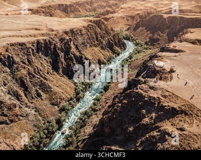 Vue aérienne du Canyon Charyn avec ses formations rocheuses multicouches colorées et sa rivière turquoise qui coule à travers le paysage aride du Kazakhstan Banque D'Images