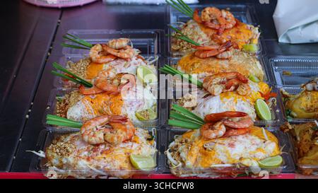 Tamponnez le papier à rouler thaï avec des crevettes, du citron vert et des cacahuètes dans une boîte à emporter transparente. Cuisine de rue thaïlandaise authentique avec une présentation lumineuse et appétissante. Banque D'Images