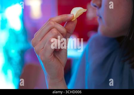 Une jeune femme ramassant des chips servait de collation dans un bar Banque D'Images