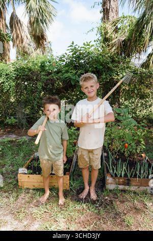 Deux garçons s'occupent des plantes dans un jardin Banque D'Images