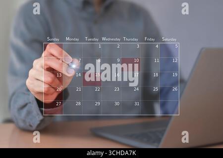 Calendrier pour les rendez-vous mensuels et la planification, gestion de son horaire d'affaires, main marquant les dates sur le calendrier virtuel Banque D'Images