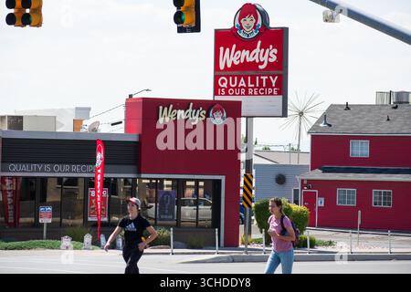 Provo, Utah — 1er septembre 2025 : deux piétons se croisent devant un restaurant de restauration rapide Wendy’s à une intersection de rues à Provo, Utah, États-Unis. Banque D'Images