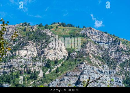 Provo Canyon, Utah, États-Unis — 1er septembre 2025 : une vue depuis Bridal Veil Falls capture des falaises rocheuses abruptes et une végétation éparpillée sous un ciel bleu clair. Banque D'Images