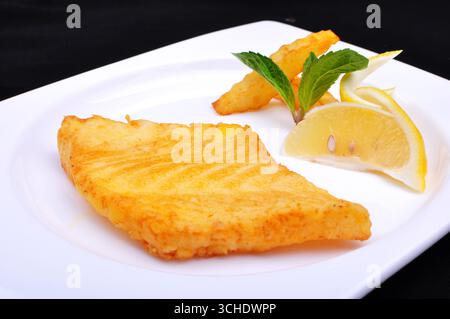 Filet de morue poêlé avec citron et frites sur assiette blanche Banque D'Images