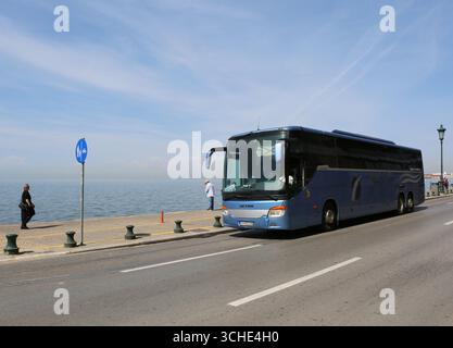 Thessalonique, Grèce-avril 23,2025:conducteur non identifié conduisant son bus touristique par la côte de la mer Égée où les gens marchent Banque D'Images