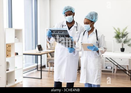 Equipe médicale en consultation examinant les radiographies et les notes médicales en clinique Banque D'Images