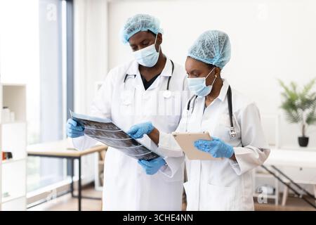 Equipe médicale en consultation examinant les radiographies et les notes médicales en clinique Banque D'Images