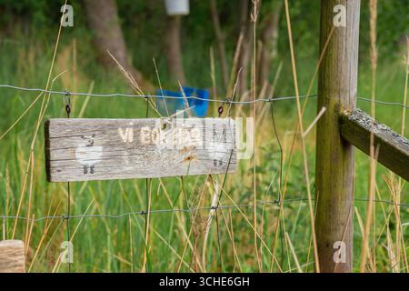 Panneau d'avertissement sur la clôture d'un pâturage de moutons dans un village suédois. Vie agricole rurale, sécurité rurale, élevage durable et respect de l'environnement Banque D'Images