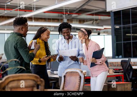 Collaboration dans un bureau moderne, équipe diversifiée examinant des documents et partageant activement des idées Banque D'Images