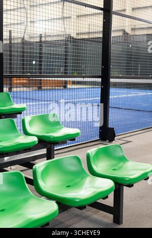 Sièges vert vif doublés de métal dans la salle de sport surplombant la cour derrière la clôture en treillis métallique Banque D'Images