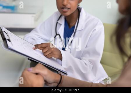 Gros plan du médecin tenant le presse-papiers, pointant sur des informations écrites Banque D'Images