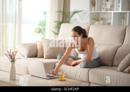 Joyeux yogi préparant des cours de yoga en ligne sur un canapé à la maison en utilisant une tablette Banque D'Images