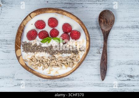 Bol en noix de coco Smoothie aux framboises, d'avoine, graines de tournesol et graines de chia pour le petit déjeuner , close up. Le concept de la saine alimentation, superfood. Banque D'Images