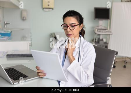 Médecin lisant les antécédents médicaux ou les dossiers médicaux, vérifiez les informations sur le lieu de travail Banque D'Images