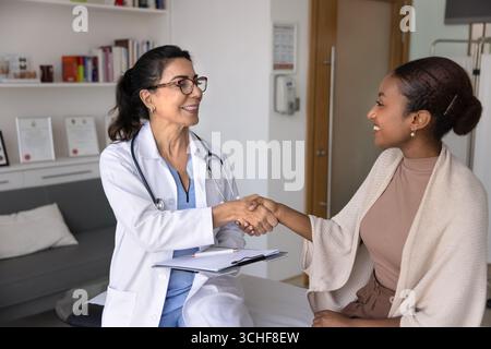 Femme patiente et cardiologue dans la poignée de main d'échange de manteau Banque D'Images
