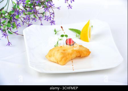 Filet de morue poêlé avec citron sur assiette blanche Banque D'Images