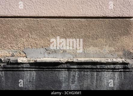 Cette image affiche un fond abstrait avec des couches de surfaces murales texturées, mettant en valeur les effets du temps et des éléments. Banque D'Images
