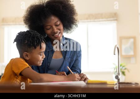 Mère et enfant dessinant ensemble à la table de la cuisine, profitant du temps créatif Banque D'Images