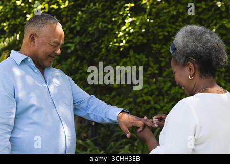Au mariage, couple senior échangeant des anneaux à l'extérieur, célébrant l'amour et l'engagement ensemble Banque D'Images