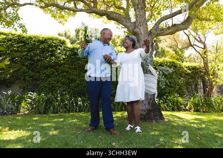 Au mariage, couple Senior dansant joyeusement dans le jardin, célébrant l'amour et le bonheur ensemble Banque D'Images
