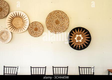 Paniers tissés faits à la main avec des motifs ethniques accrochés sur le mur blanc comme décoration intérieure de style bohème. Banque D'Images