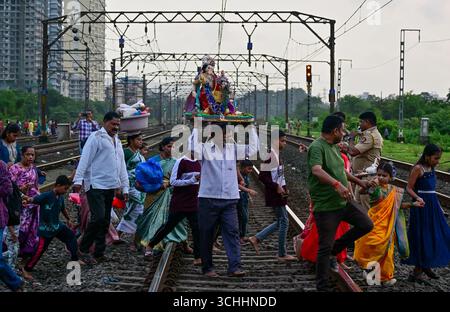 Kalyan, Mumbai, Maharashtra, Inde, 02-09-2025-les dévots hindous portent les idoles du Seigneur Ganesh et de la déesse Gauri traversant les voies ferrées pour l'immersion. Banque D'Images