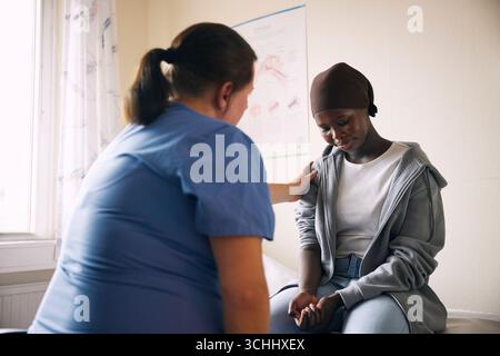 Une travailleuse de santé consolant une fille triste en salle d'examen à l'hôpital Banque D'Images