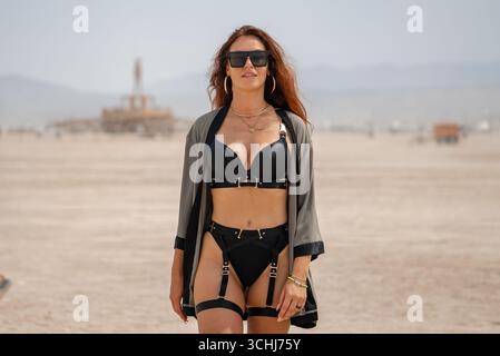 Femme en tenue de harnais marchant près de Burning Man Effigy dans le désert du Nevada Banque D'Images
