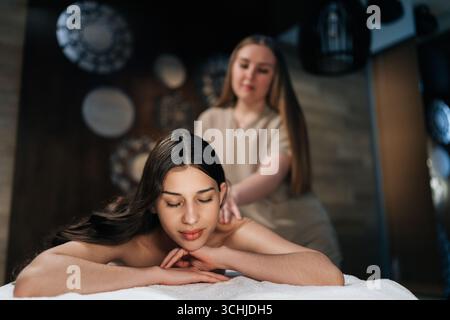 Gros plan portrait d'une jeune femme couchée les yeux fermés dans un centre de bien-être pendant la massothérapie. Portrait de belle cliente féminine se relaxant Banque D'Images