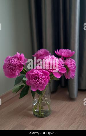 Un buquet d'azalées sur un plancher en bois et épais rideau vert satiné comme fond Banque D'Images