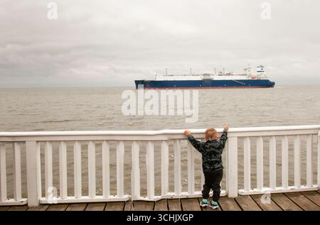 Photo montrant un grand porte-conteneurs passant devant la ville allemande de Cuxhaven à l'embouchure de l'Elbe Banque D'Images