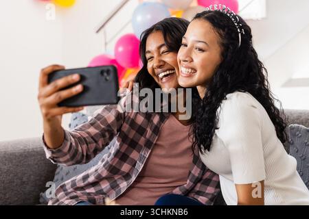 Prise de selfie, mère souriante et fille célébrant leur anniversaire ensemble à la maison Banque D'Images
