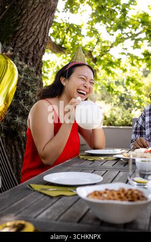 À la fête, femme en robe rouge riant tout en tenant ballon à la célébration sur le pont Banque D'Images