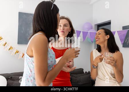 Trois jeunes femmes, une hispanique et deux caucasiennes, discutant joyeusement à la fête Banque D'Images