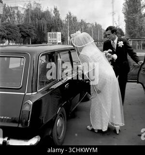 Photos d'archives en noir et blanc prises dans la ville de Sloviansk en 1976. Les cadres capturent la procession du mariage près des anciens ZAGS (bureau d'enregistrement) sur la rue Lénine. Les jeunes mariés montent dans des voitures soviétiques décorées, une prestigieuse gaz-21 'Volga' et une VAZ 'Zhiguli' à la mode. Les scènes de rue transmettent l'atmosphère animée et les traditions d'un mariage soviétique, ainsi que le look quotidien de Sloviansk dans les années 1970 Banque D'Images