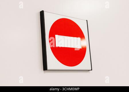 Un panneau circulaire rouge d'interdiction d'entrée avec une bande horizontale blanche est monté sur un mur blanc propre. Le panneau indique clairement l'accès restreint dans le Banque D'Images