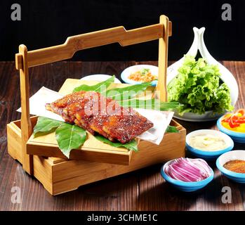 Poitrine de porc grillée coréenne avec laitue et condiments sur plateau en bambou Banque D'Images