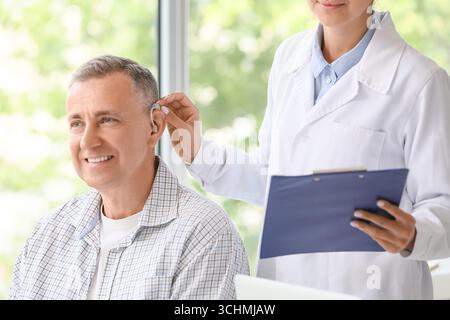 Homme mature avec prothèse auditive visitant le médecin en clinique Banque D'Images