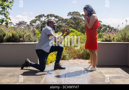 Homme proposant de surprendre femme dans le jardin, à la fois souriant et joyeux Banque D'Images