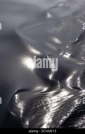 Gros plan abstrait de l'eau arctique froide avec des ondulations lisses et des tons métalliques. La lumière du soleil et les reflets du ciel créent un effet de métal fondu sur le propre, Banque D'Images