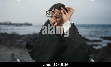 Femme en uniforme de juge au bord de la mer ajustant les lunettes avec fond de mer Banque D'Images