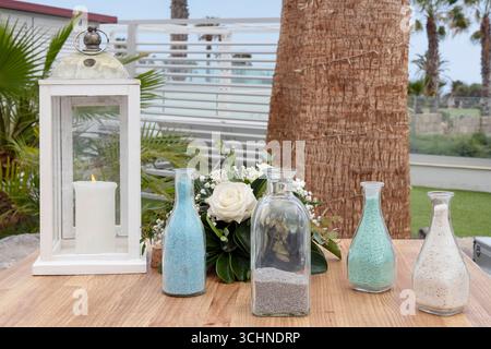 Configuration de cérémonie de sable de mariage sur une table en bois à l'extérieur avec quatre bouteilles en verre transparent remplies de sable de couleur différente utilisé dans un rituel d'unité Banque D'Images